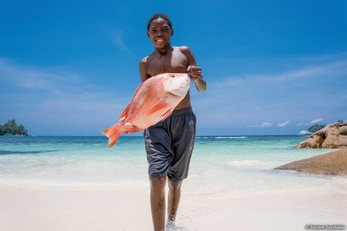 Jeune vendeur de poisson sur une plage de l'île de Mahé aux Seychelles