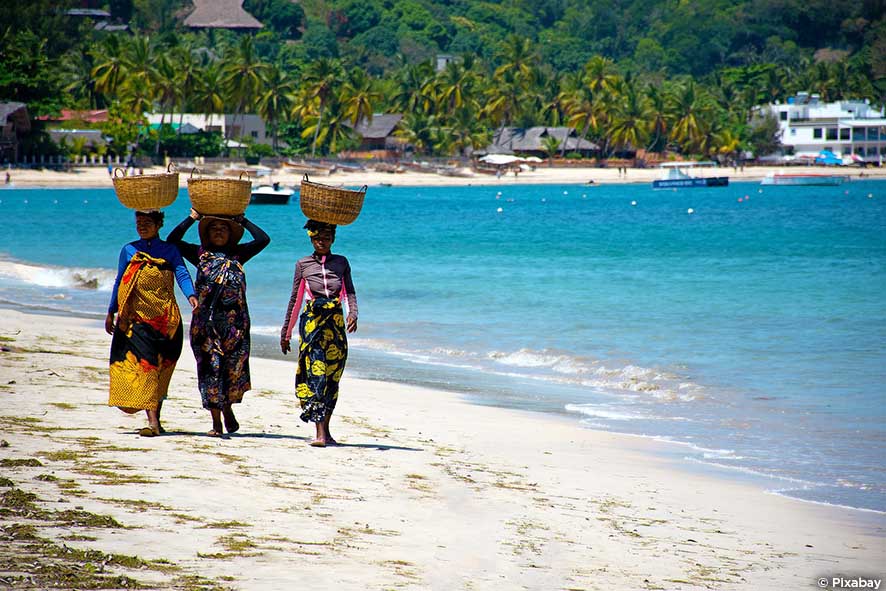 Femmes malgaches sur la plage transportant des paniers sur leur tête
